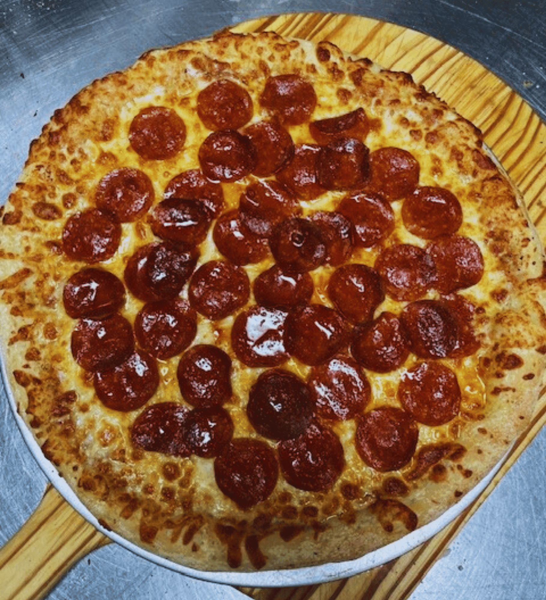 A freshly baked pepperoni pizza on a wooden peel.