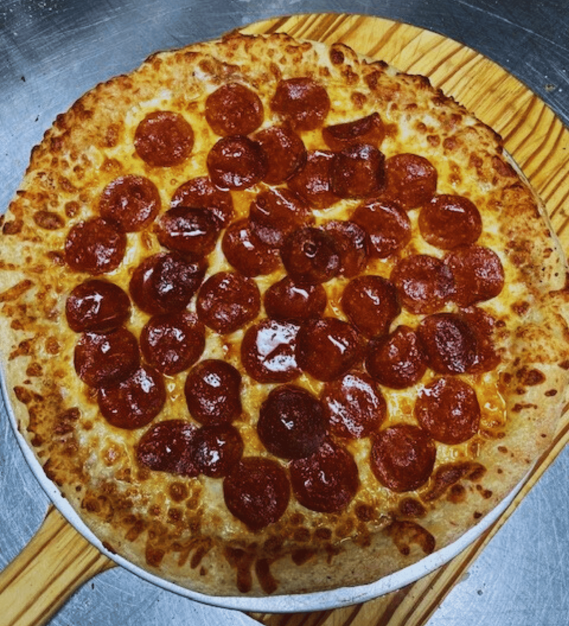 A freshly baked pepperoni pizza on a wooden peel.